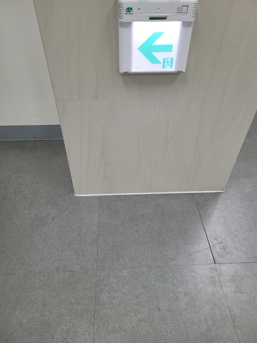 타일 부분수리 — 벽 모서리 마감 후, 비상구 안내등 옆까지 깔끔
